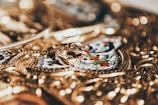 Intricate gold jewelry serves as a detailed background with ornate engravings, featuring two elegant gold rings placed prominently at the center.