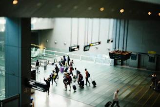 A group of travelers with luggage walking through a modern airport terminal