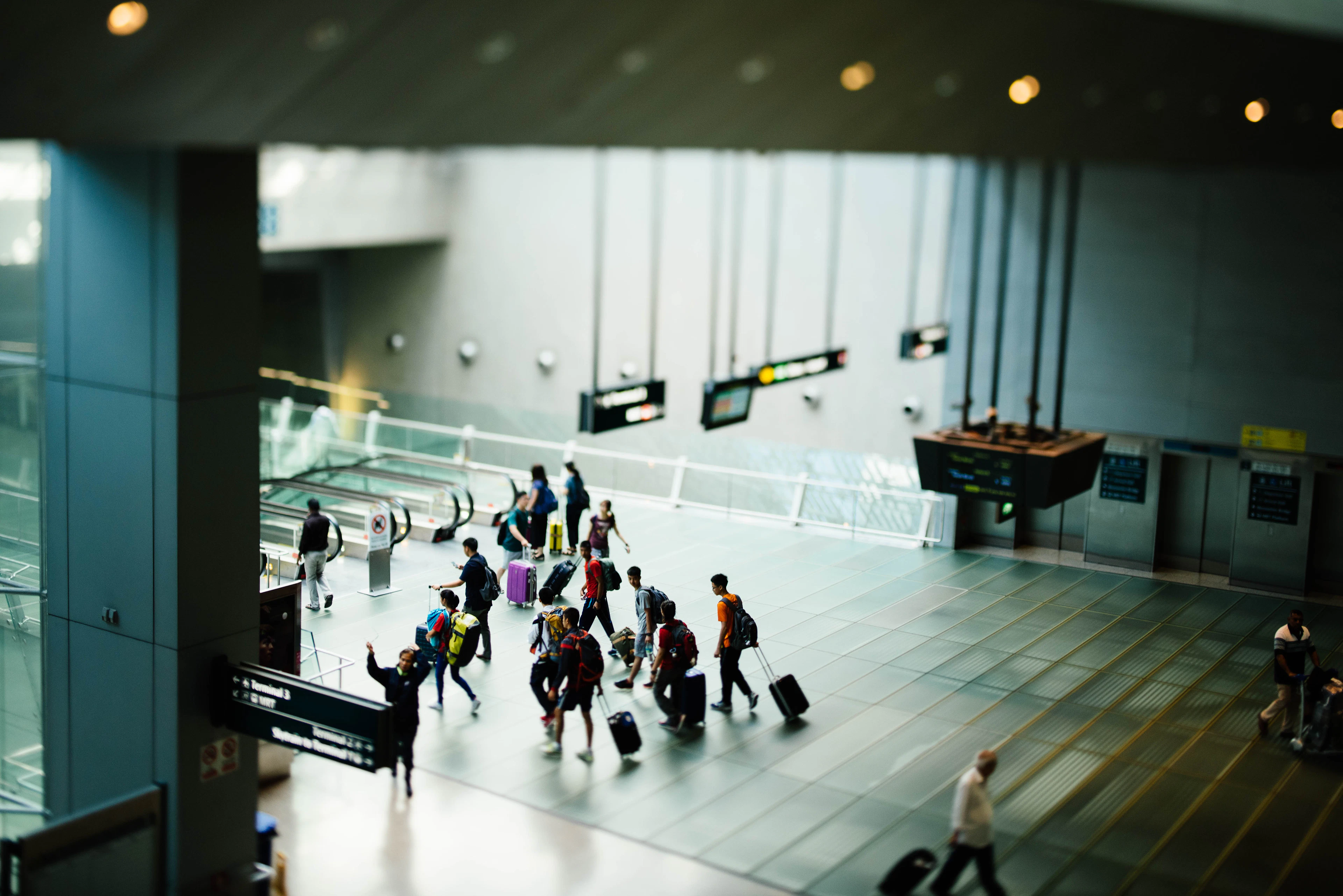 Travellers with luggage walking through a modern airport terminal