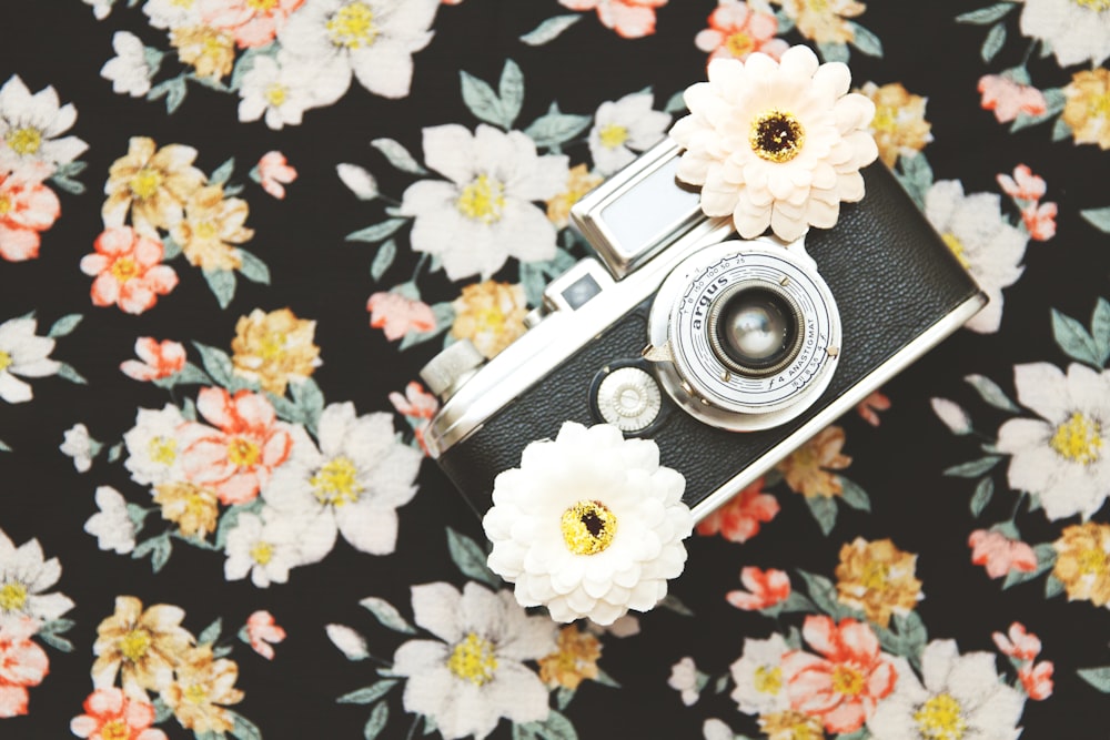 black and silver SLR camera with white flowers