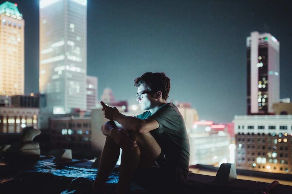 man sitting on top of building during nighttime