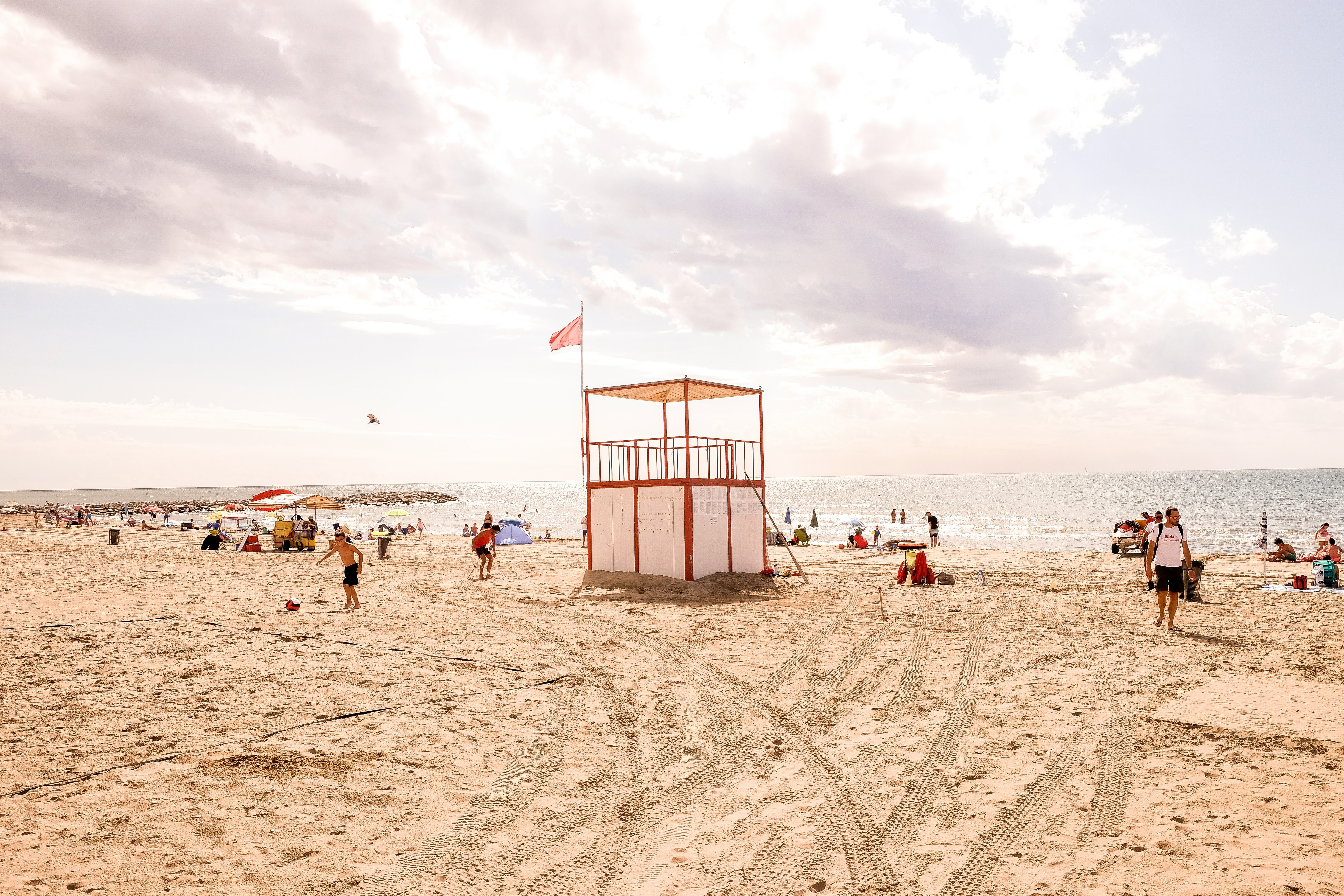 white and red wooden lifeguard tower surrounded by people near ocean during daytime