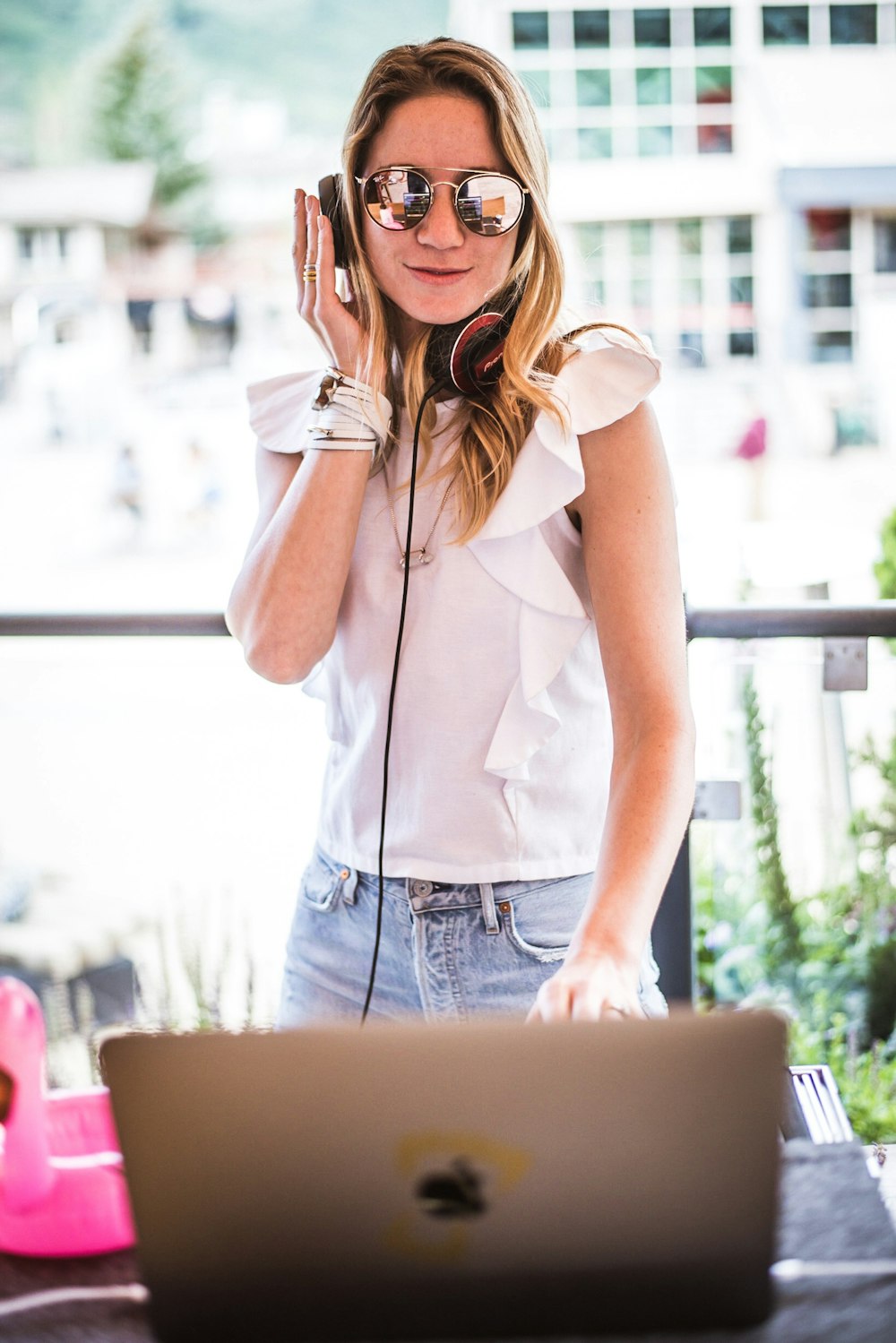 Mujer de pie frente a una computadora portátil plateada con auriculares