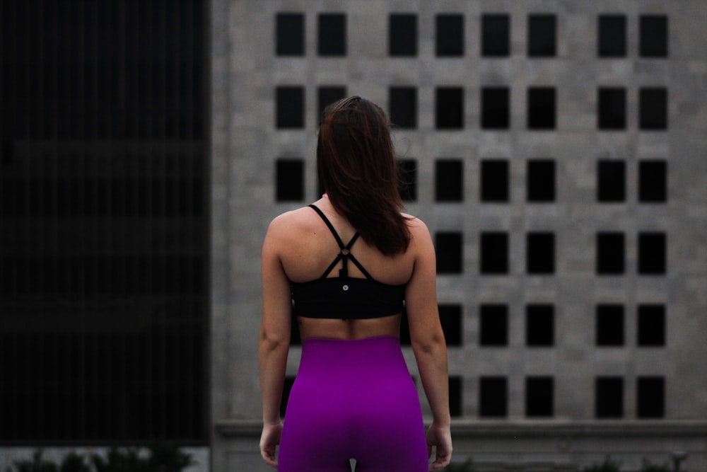 femme debout devant un bâtiment gris pendant la journée