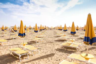 Colorful beach umbrellas and sun loungers on golden sand under a clear sky.