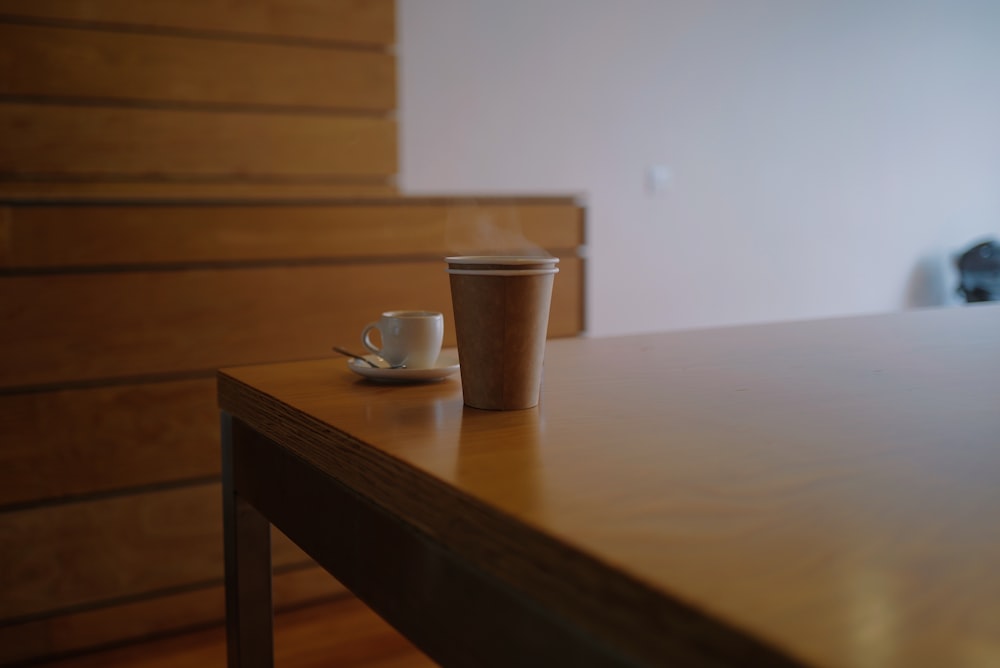 uma xícara de café sentada em cima de uma mesa de madeira