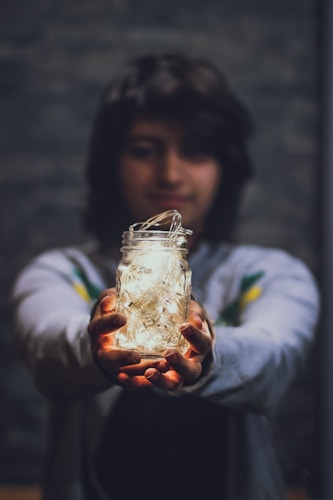 person holding glass jar with LED string