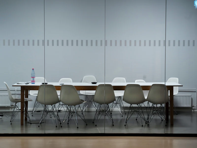 A long empty meeting table lined with chairs in a bright room