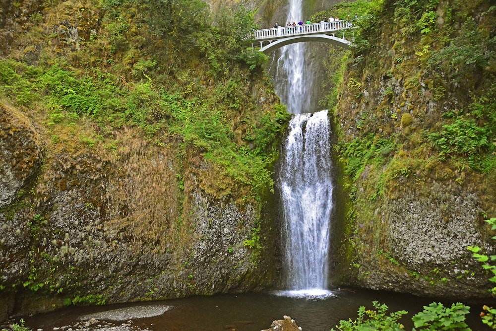 people standing on bridge above waterfalls during daytime
