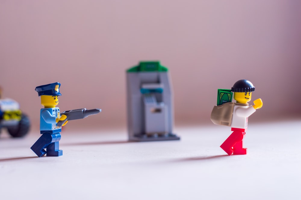 A Lego police officer pointing his gun at a robber.
