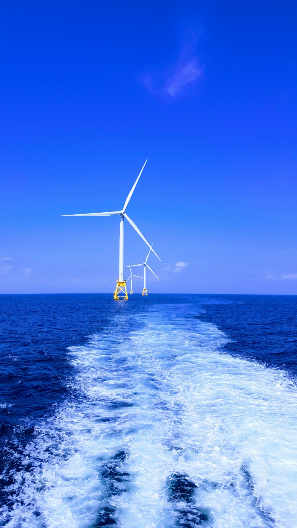 trois éoliennes blanches sur la mer