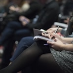 selective focus photography of people sitting on chairs while writing on notebooks