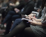 selective focus photography of people sitting on chairs while writing on notebooks