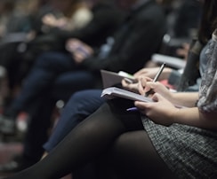 selective focus photography of people sitting on chairs while writing on notebooks