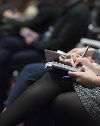 selective focus photography of people sitting on chairs while writing on notebooks