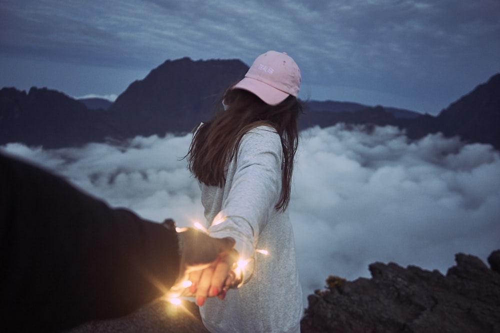 femme tenant la main d’une personne devant des nuages