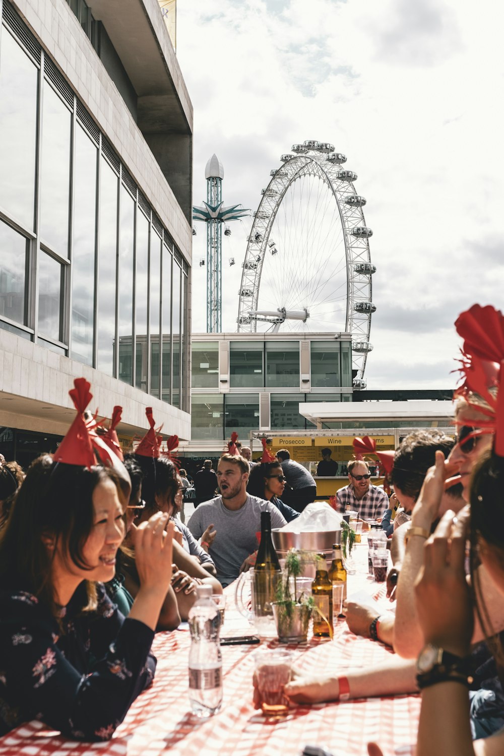 people dining outside building near ferris wheel