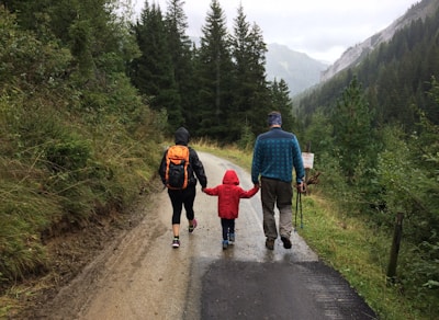 man, woman, and child walking together along dirt road