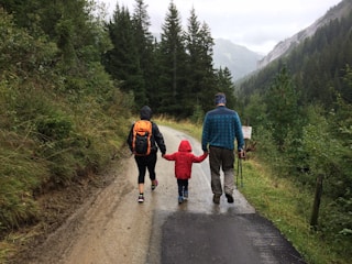 man, woman, and child walking together along dirt road
