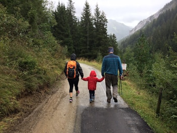 man, woman, and child walking together along dirt road