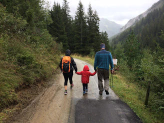 man, woman, and child walking together along dirt road