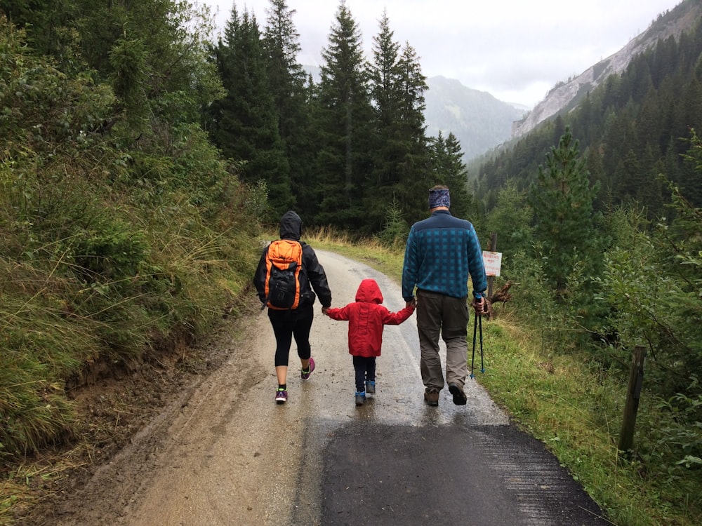 man, woman, and child walking together along dirt road