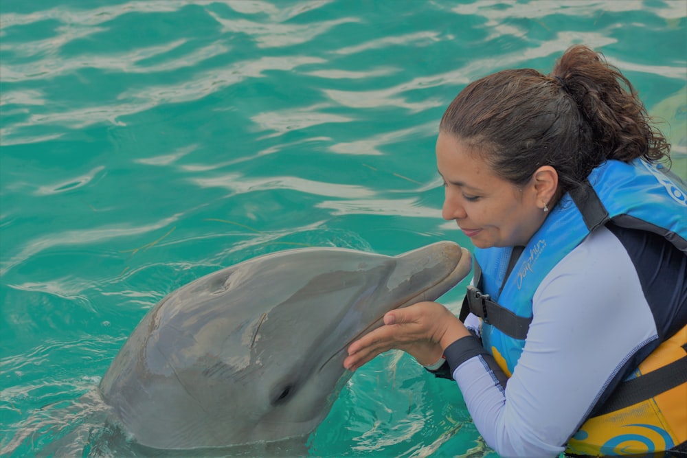 Frau spielt mit Delfin im Gewässer