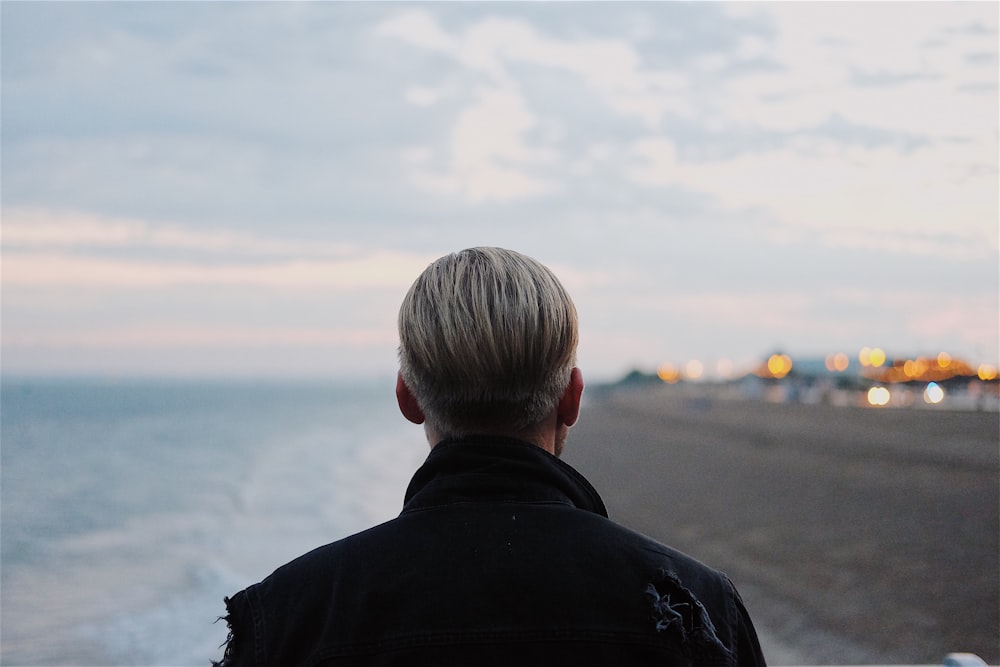 man in black coat walking on seashore