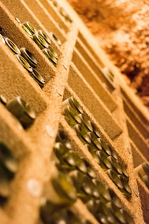 Wide-angle shot of a cellar room filled with rows of precious wine bottles stacked horizontally, showcasing the depth of our exclusive collection.