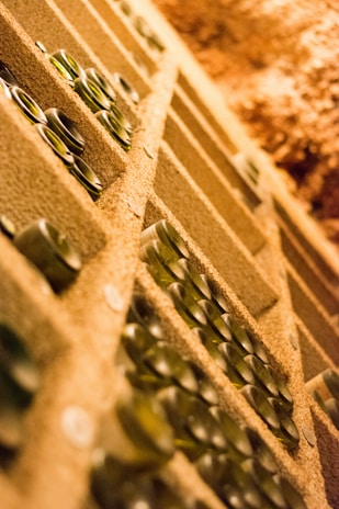 Wide-angle shot of a cellar room filled with rows of precious wine bottles stacked horizontally, showcasing the depth of our exclusive collection.