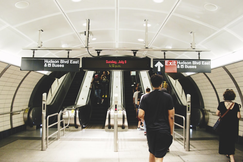 people walking towards escalator inside Bus station