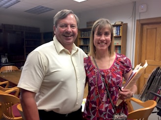 A happy couple reviewing property listings with a realtor in an office.