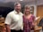 A smiling real estate agent showing a property to a couple in a bright living room.