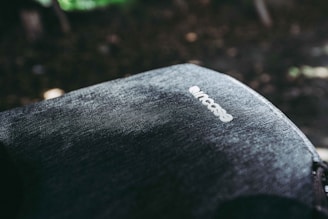 A close-up view of a fabric surface of a backpack with the brand name 'Incase' visible on it. The texture of the material is detailed, showing a rugged or denim-like appearance. The lighting creates shadows and highlights, adding depth to the image.