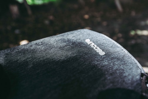 A close-up view of a fabric surface of a backpack with the brand name 'Incase' visible on it. The texture of the material is detailed, showing a rugged or denim-like appearance. The lighting creates shadows and highlights, adding depth to the image.