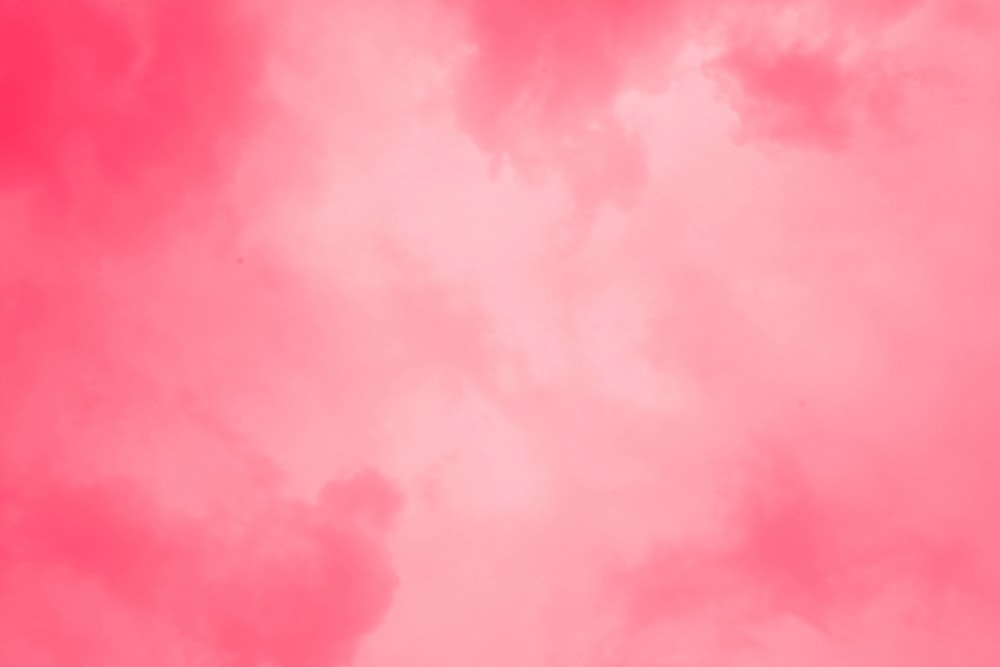 Un cielo rosa con un avión volando en el cielo
