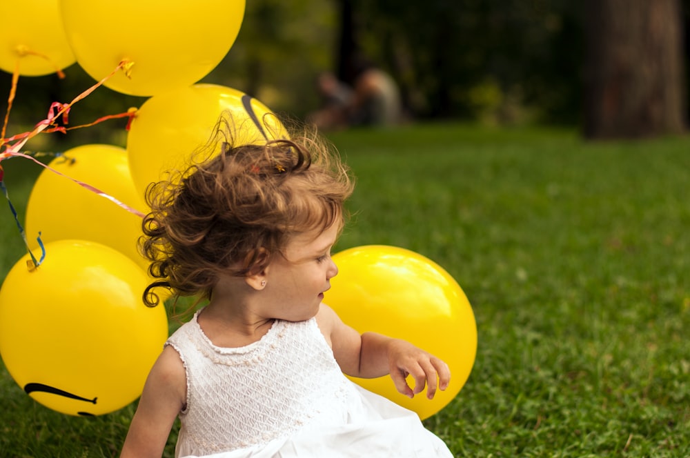 girl sitting on grass near balloon