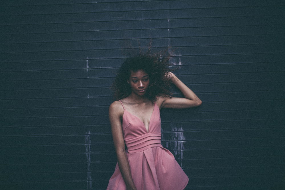 Mujer en vestido apoyada en la pared negra