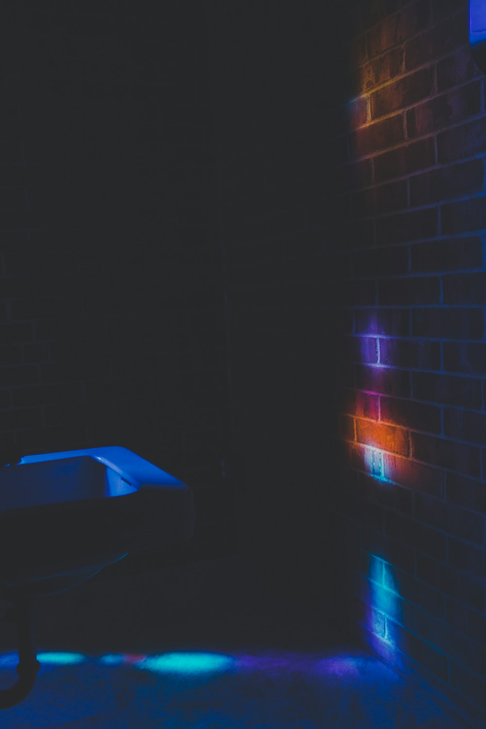 a dark room with a toilet and a brick wall