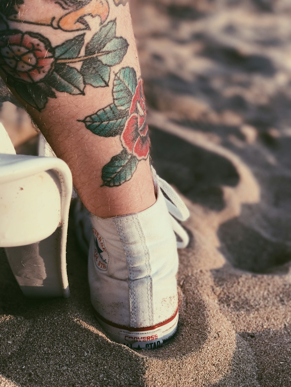 person with red rose tattoo on left leg