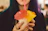 Smiling woman holding a tropical drink with a colorful beach backdrop.