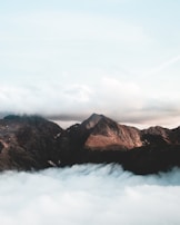 A serene mountain range seen from above, with clouds gently hugging the peaks.