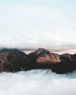 A serene mountain range seen from above, with clouds gently hugging the peaks.