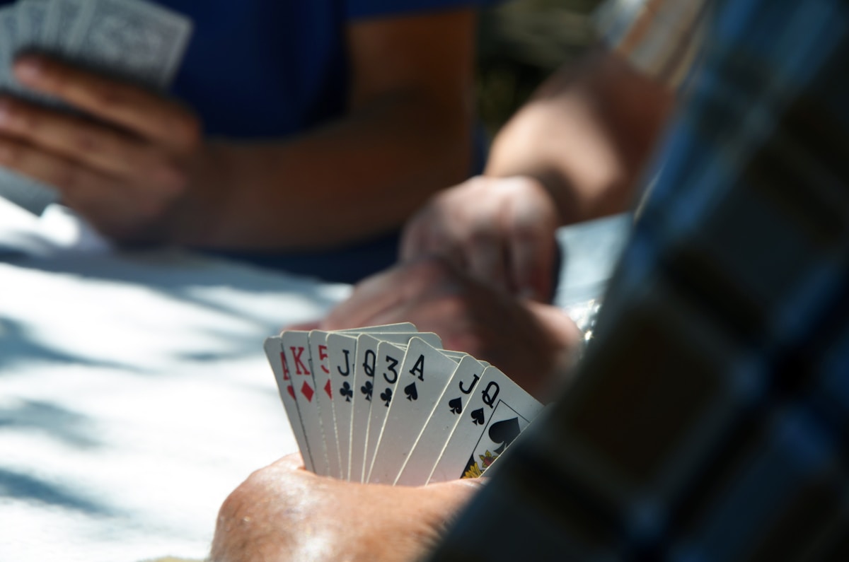 People playing cards. Close up of a person with a blue checkered shirt holding several playing cards.