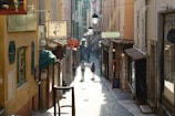 A cinematic shot of a couple walking hand-in-hand along a cobblestone street in a quaint French village.