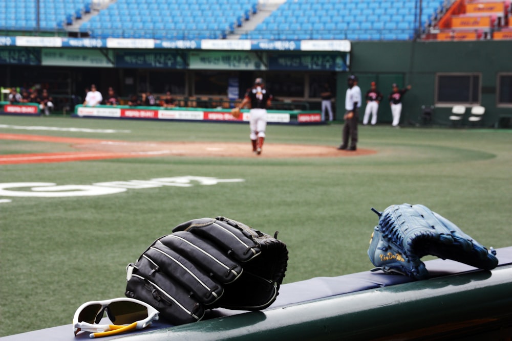 two black and blue baseball mitts on rail