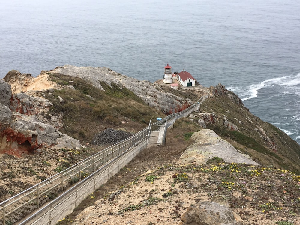 stairs going towards lighthouse beside the edge of a island during day