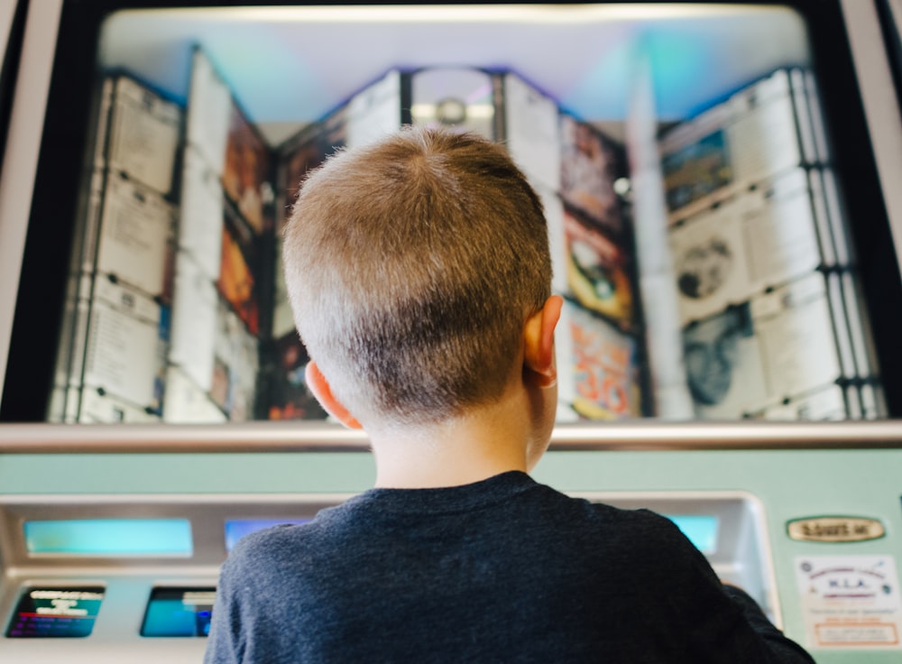 boy wearing black shirt on teal machine