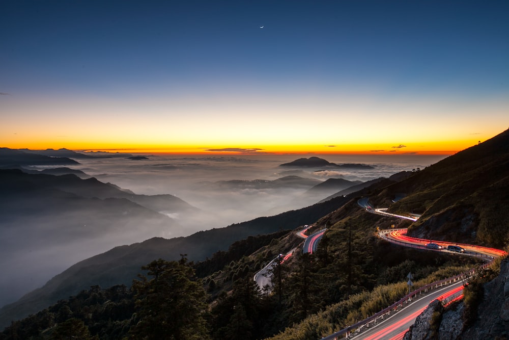 time lapse photo of car lights on mountain road during nighttime