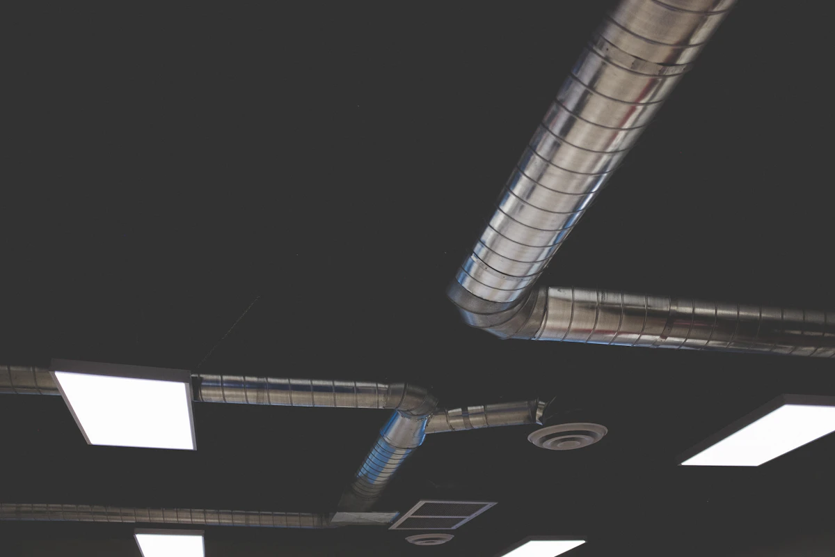 Bulky round spiral ductwork routed along an exposed ceiling
